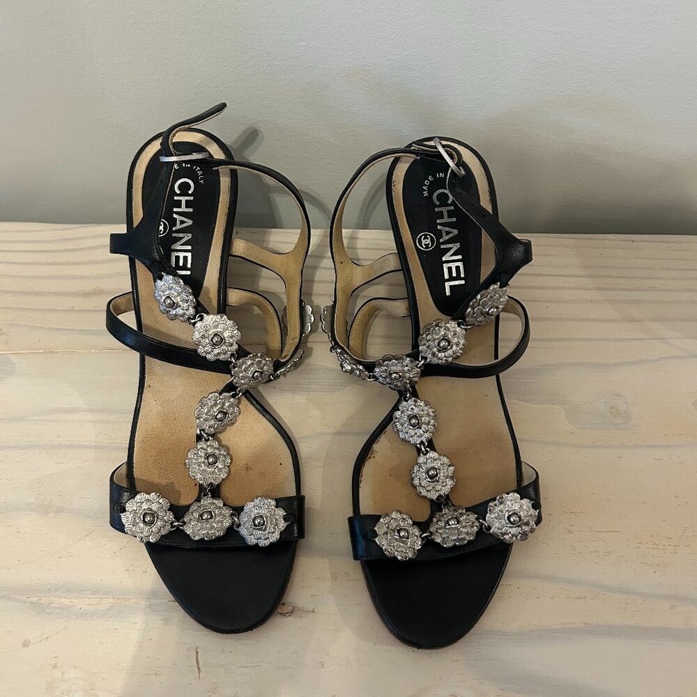 CHANEL black sandals with silver Camellia flower embellishments.